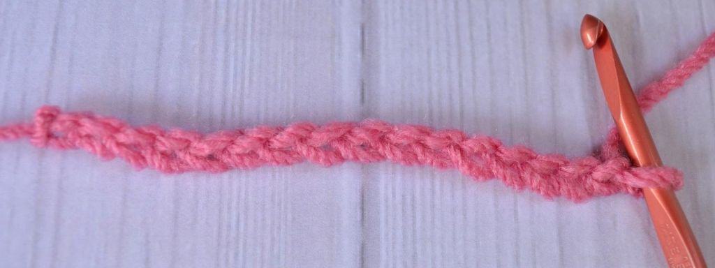 Foundation chain of double crochet stitches in pink yarn