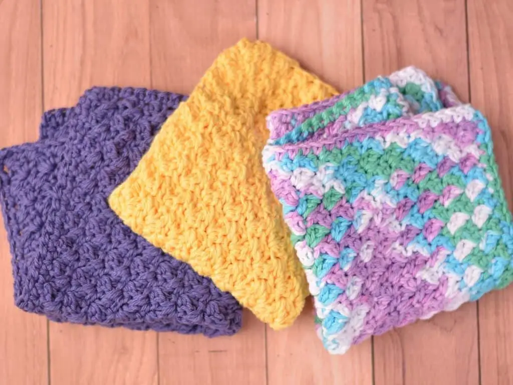 Three washcloths folded in dark orchid, yellow and beach ball blue colors