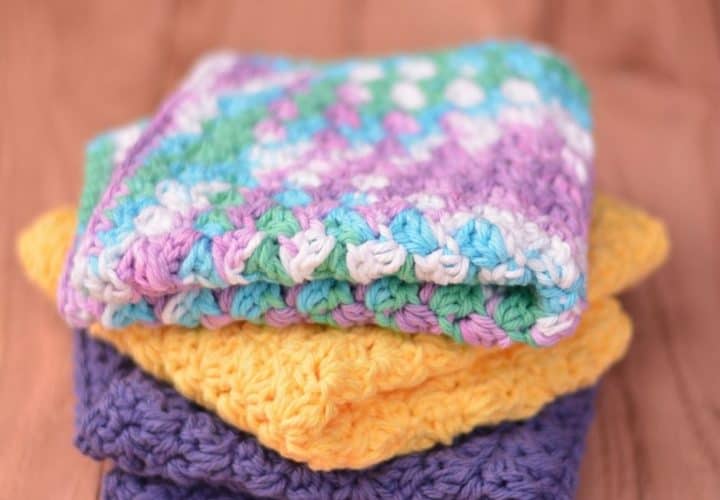 Stack of three folded crochet washcloths in multiple colors.