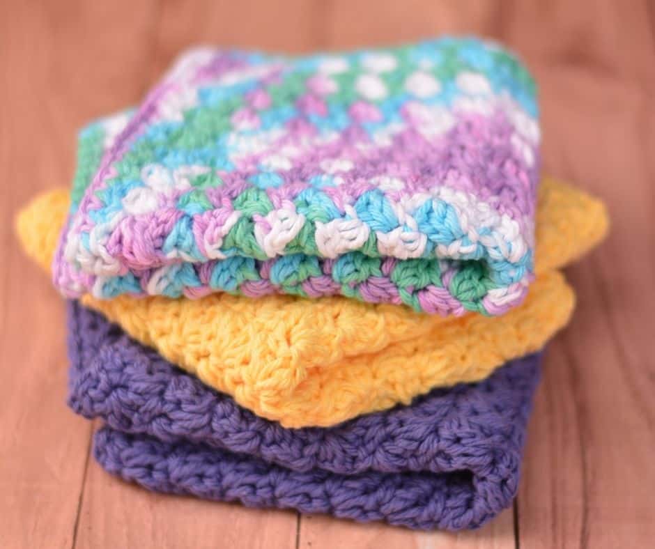 Stack of three folded crochet washcloths in multiple colors.