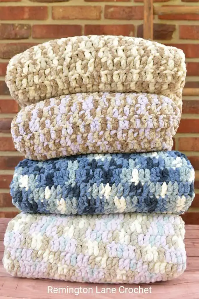 Stack of four folded crochet baby blankets.