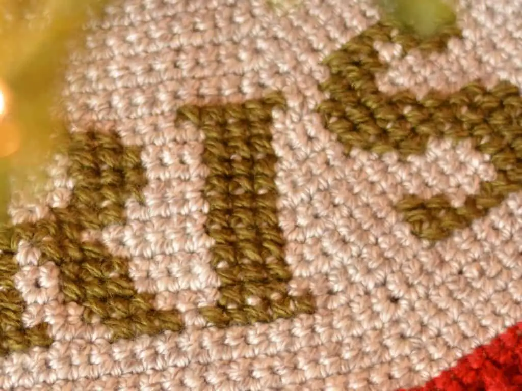 Close up of cross stitch on top of crochet tree skirt to create monogram lettering