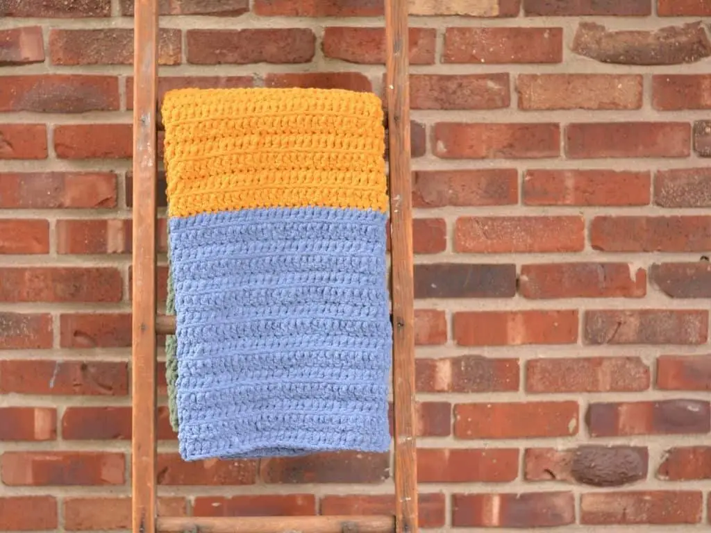 Blue and gold baby blanket draped over an antique ladder