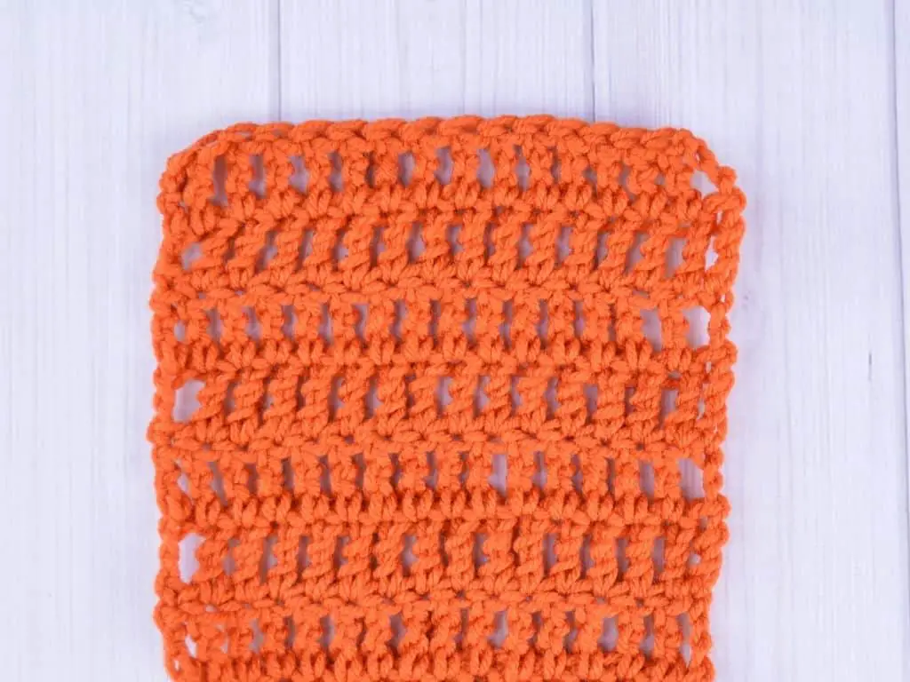 Small swatch of bright orange yarn made with treble crochet stitches