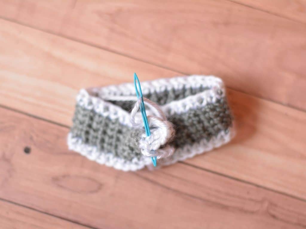 A crochet headband being sewn together into one piece