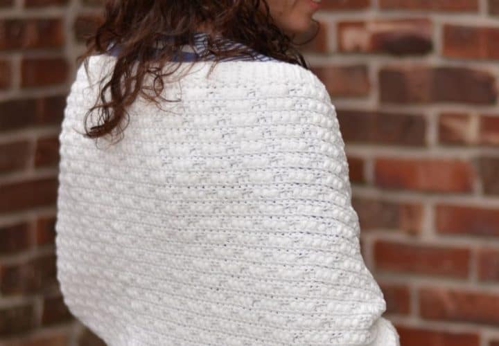 The back view of a woman wearing a textured white cozy shawl