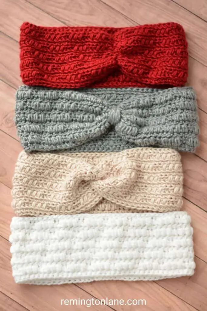 Four crochet ear warmers in different colored yarn laying flat on a table.