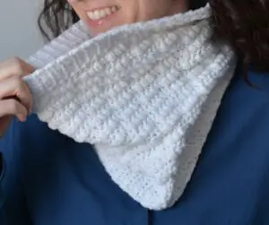A close-up of a woman wearing a white crochet neck warmer