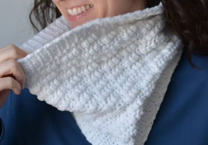 A close-up of a woman wearing a white crochet neck warmer