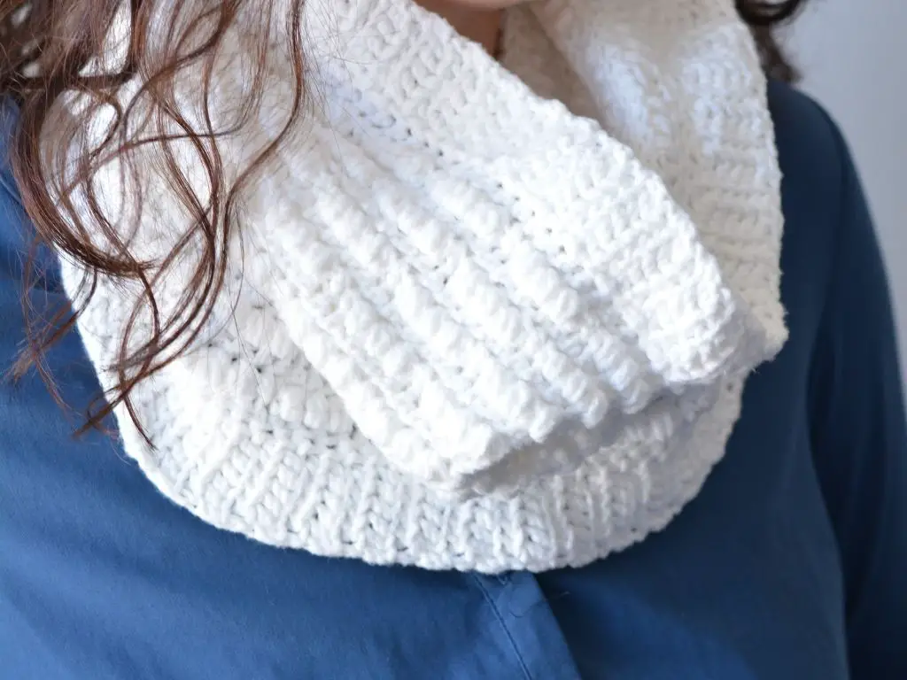 Close up of a white cowl crocheted with different textured stitches