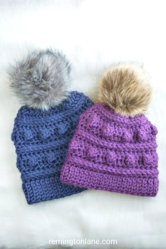 Two bulky handmade winter hats on a table.