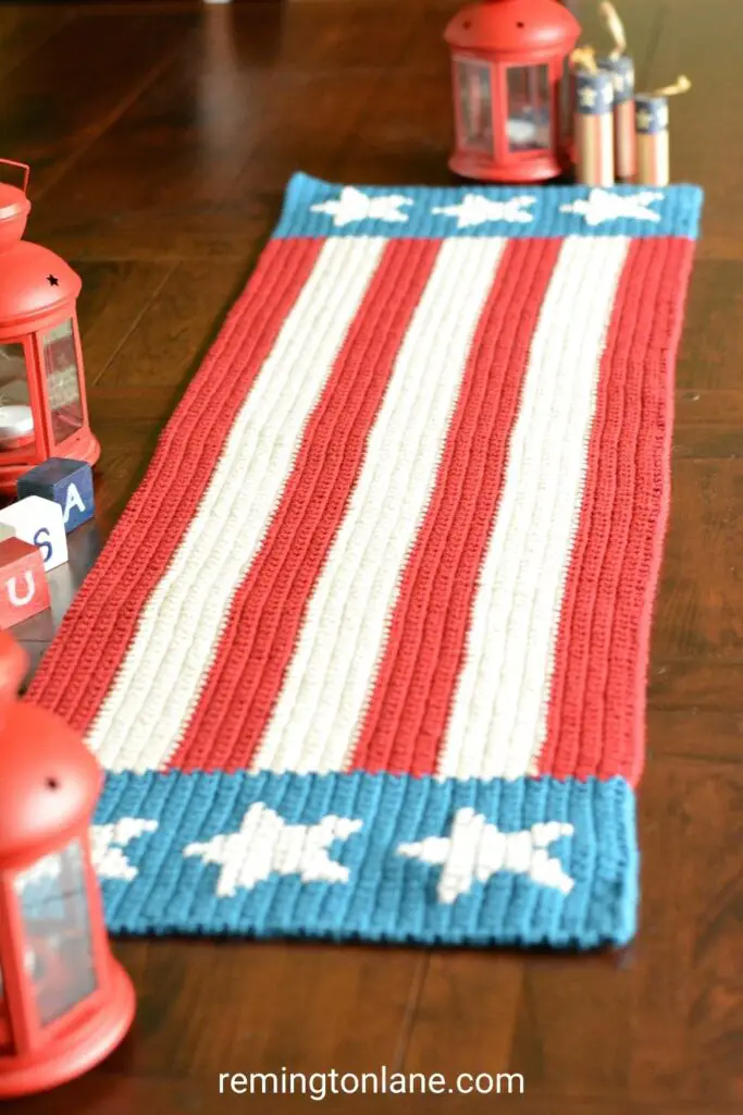 Wooden table with 4th of July table runner, red candle lanterns, and vintage wooden candles