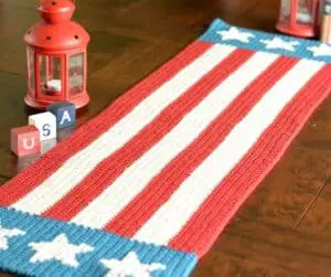 A crocheted table runner with red and white stripes on a table