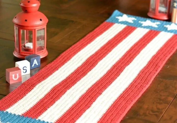 A crocheted table runner with red and white stripes on a table