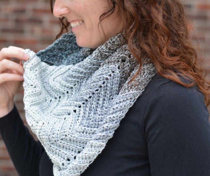 A close-up of a woman wearing a grey ombre crochet cowl