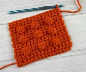 Orange yarn square with 9 bumps on it