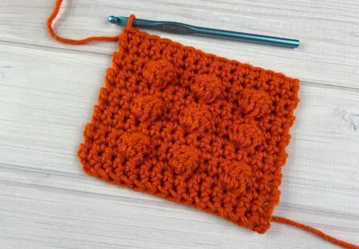 Crochet bobble stitches made from orange yarn in a small swatch.