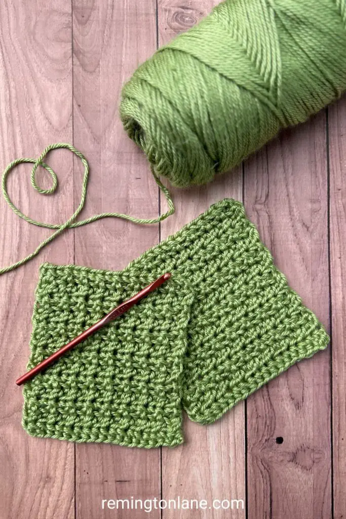 Lime green yarn with a strand forming a heart next to two crocheted premie bonding squares all laying on a wooden table.