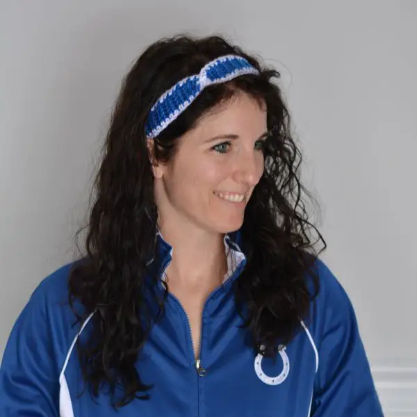 Woman wearing a blue and white team jacket and a matching headband made from yarn