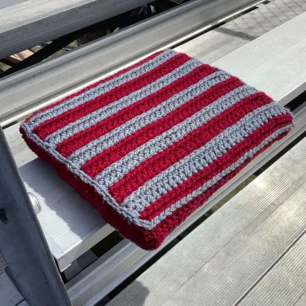 Red and grey striped bleacher cushion laying on a metal bleacher