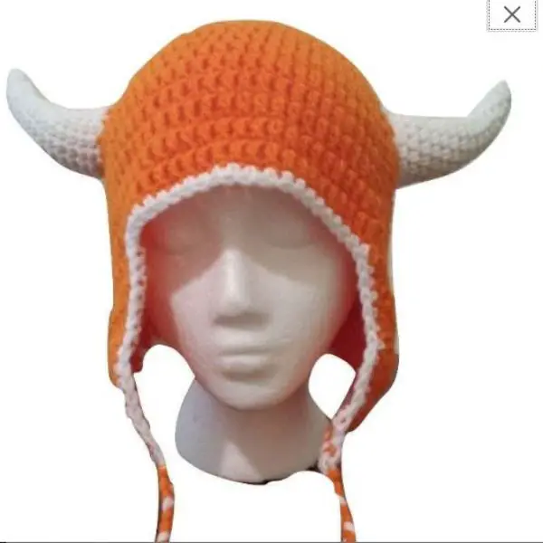 A white mannequin head wearing an orange hat made out of yarn with longhorns on it