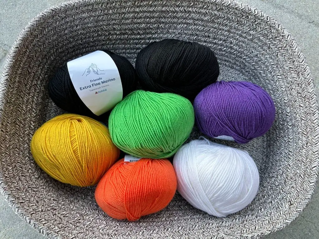 A soft-sided basket full of colorful sport weight yarn