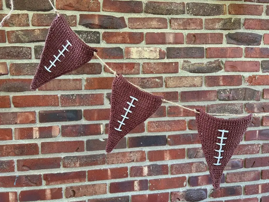 Three crochet football flags strung together into a garland with jute