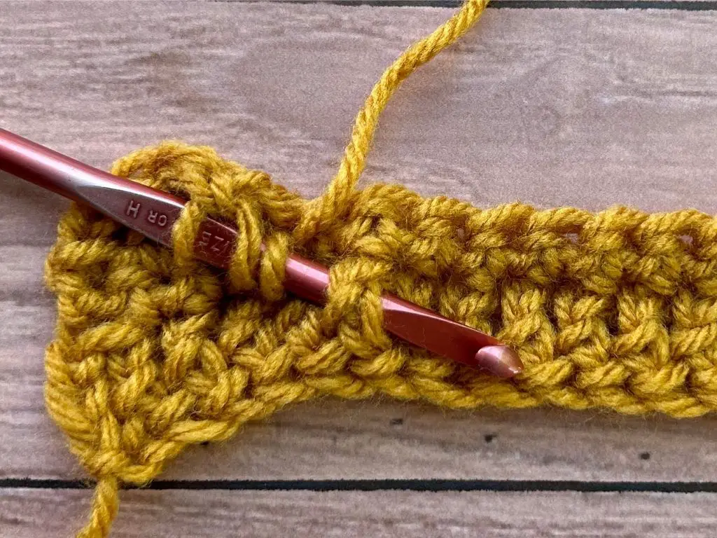 Close-up of a crochet hook demonstrating a front post treble crochet stitch