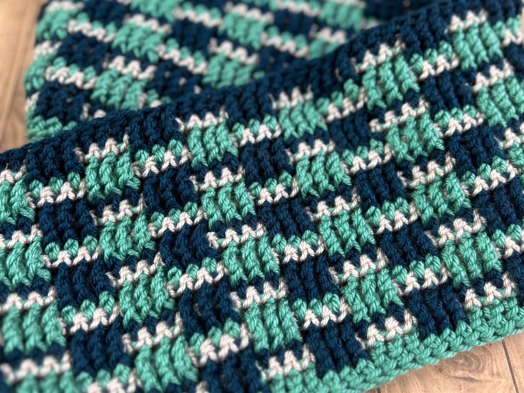 A close-up of a multi-colored women's infinity scarf that is crocheted using Lion Brand Basic Stitch yarn.