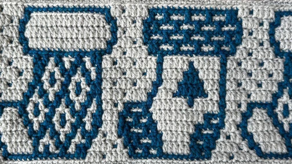 Crocheted blanket with a Christmas stocking design made with blue and grey yarn.