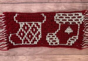 A red and cream crochet blanket swatch depicting two different mosaic Christmas stocking designs.