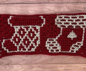 A red and cream crochet blanket swatch depicting two different mosaic Christmas stocking designs.