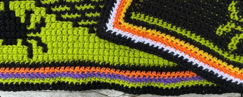 A close up of a mosaic crochet envelope border in Halloween-themed color yarn.