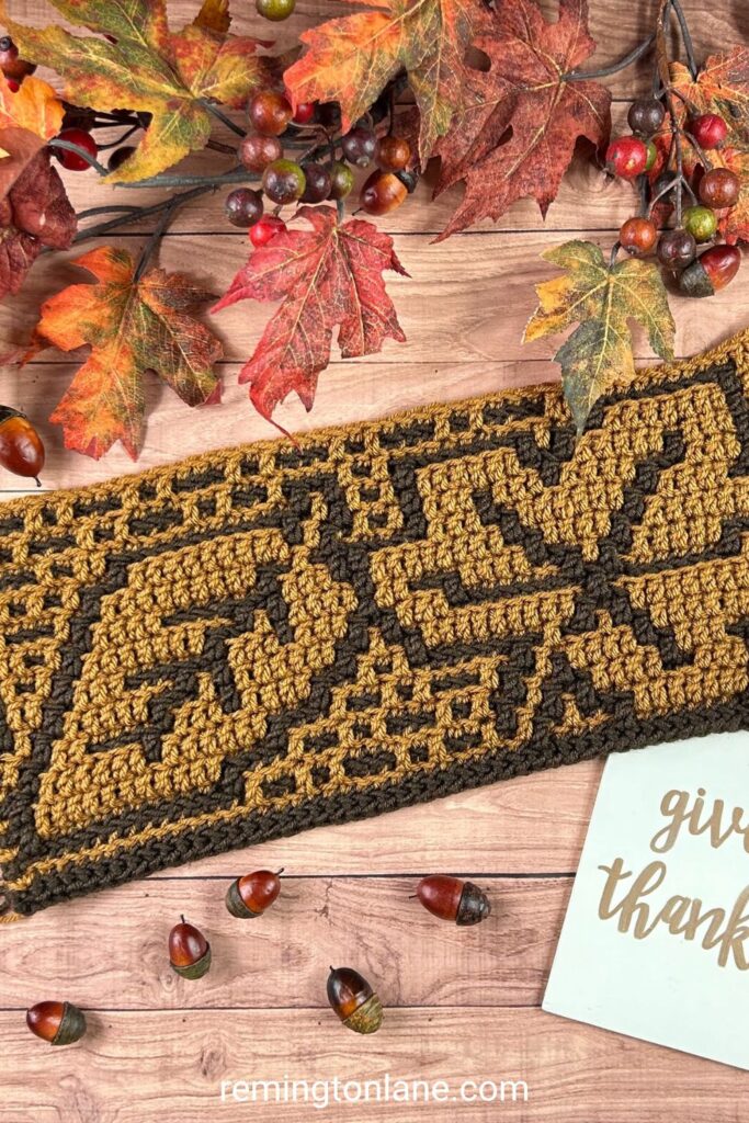 A mosaic crochet sample of a blanket section that contains two leaves made in shades of brown.