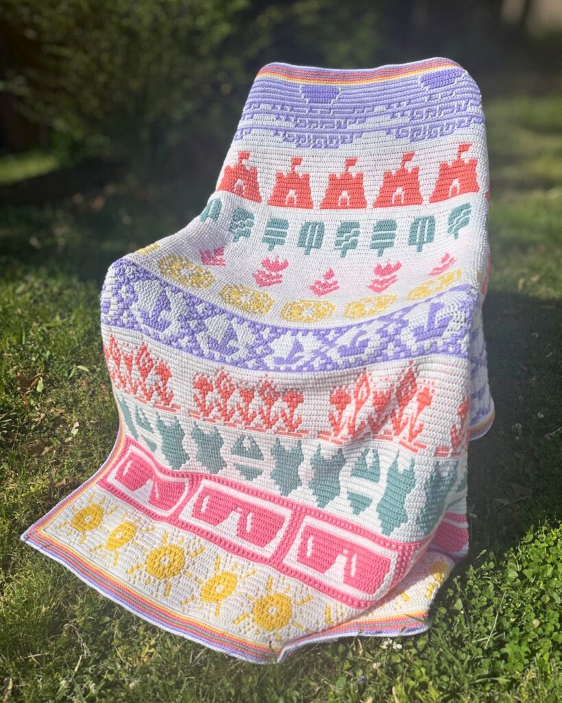 The Great Summer Mosaic Blanket draped on a chair outside in the sun