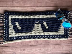 A sample of mosaic crochet sunglasses blanket section in beige and navy yarn.
