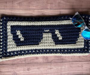 A sample of mosaic crochet sunglasses blanket section in beige and navy yarn.